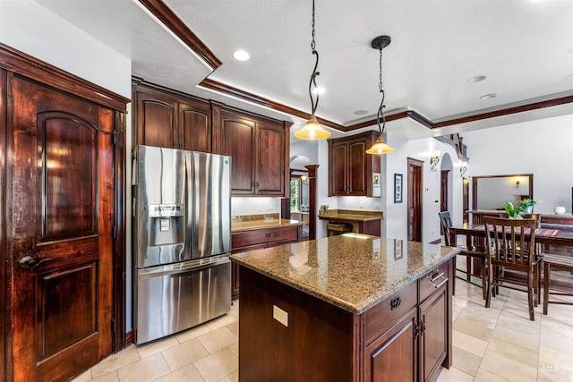 kitchen featuring pendant lighting, stainless steel refrigerator with ice dispenser, a tray ceiling, a kitchen island, and dark stone counters