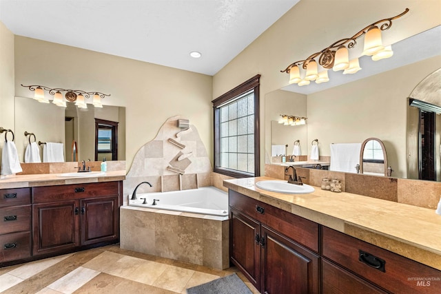 bathroom featuring two vanities, a bath, tile patterned flooring, and a sink