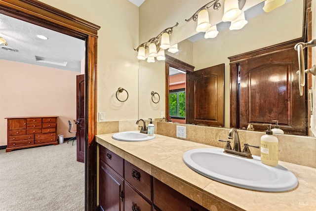 bathroom featuring double vanity, a textured ceiling, and a sink