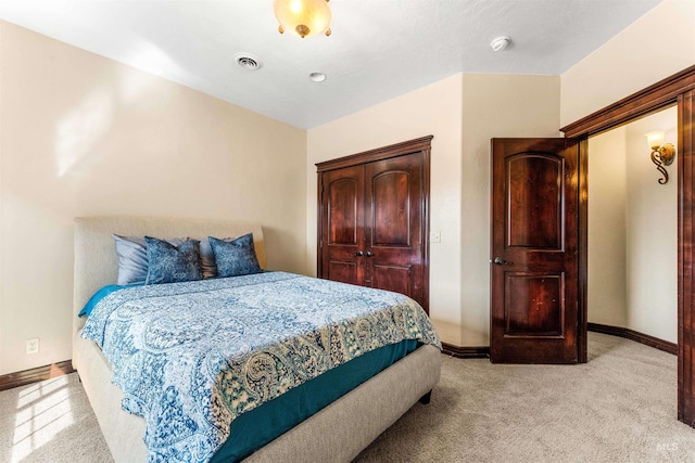 bedroom with visible vents, baseboards, a closet, and light carpet