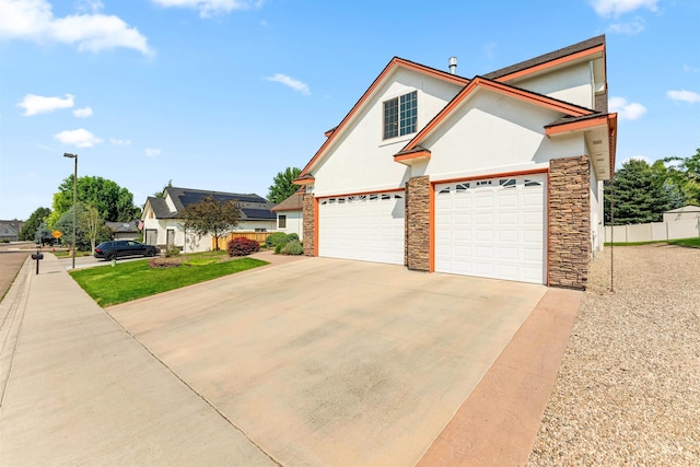 view of front of house with fence, concrete driveway, stucco siding, stone siding, and an attached garage