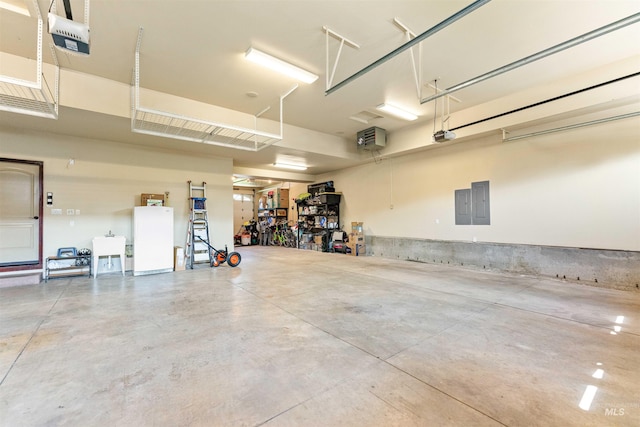 garage featuring electric panel, a garage door opener, freestanding refrigerator, and a sink