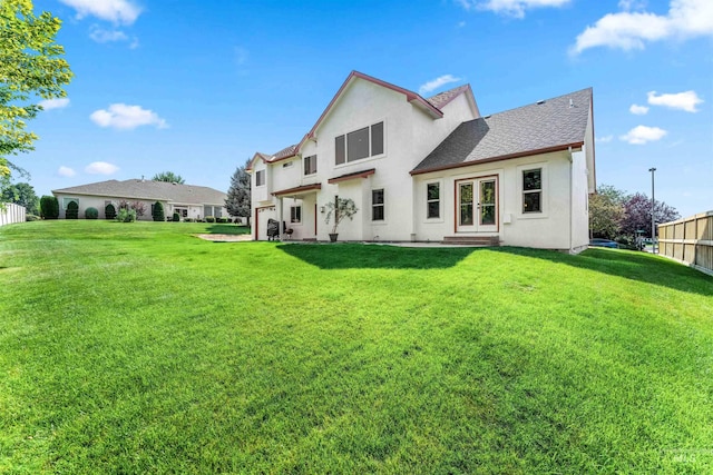 back of house featuring a lawn, fence, french doors, and stucco siding