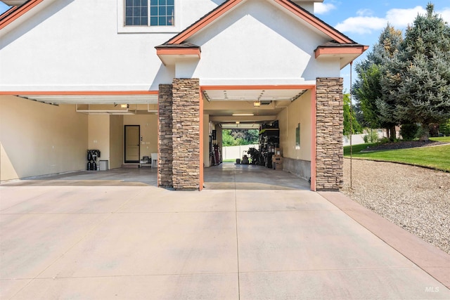 view of front facade with stucco siding, stone siding, and driveway