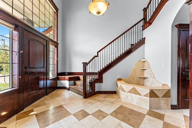 foyer entrance featuring stairway, a high ceiling, arched walkways, and a wealth of natural light