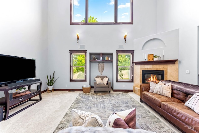 carpeted living room with baseboards, plenty of natural light, visible vents, and a tiled fireplace