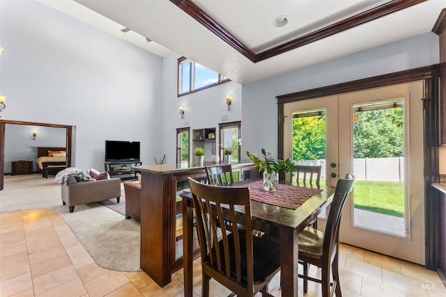 dining area featuring crown molding, a tray ceiling, light tile patterned floors, french doors, and a towering ceiling