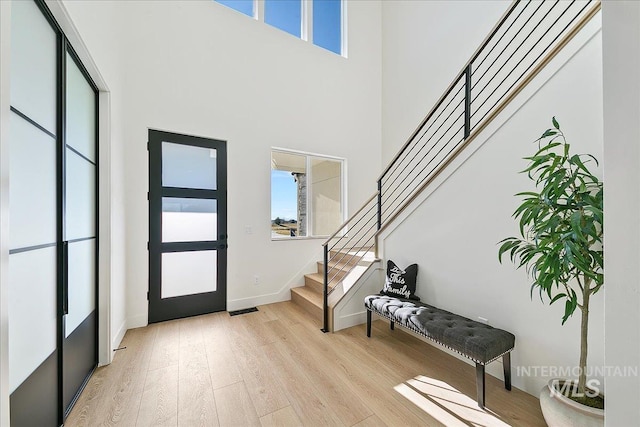 entrance foyer featuring a towering ceiling and light wood-type flooring