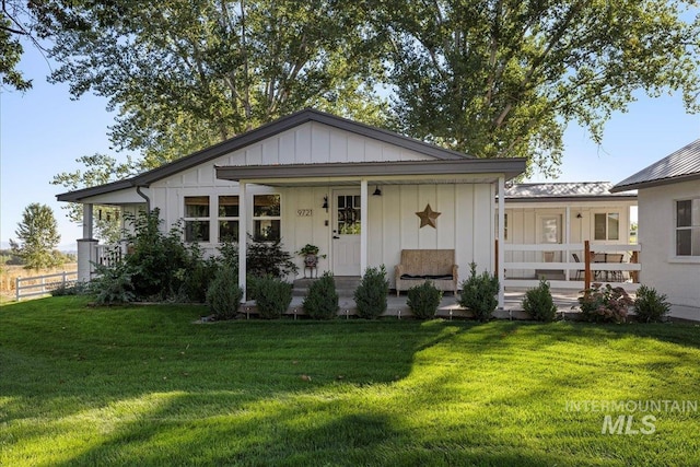 rear view of property featuring a yard and covered porch