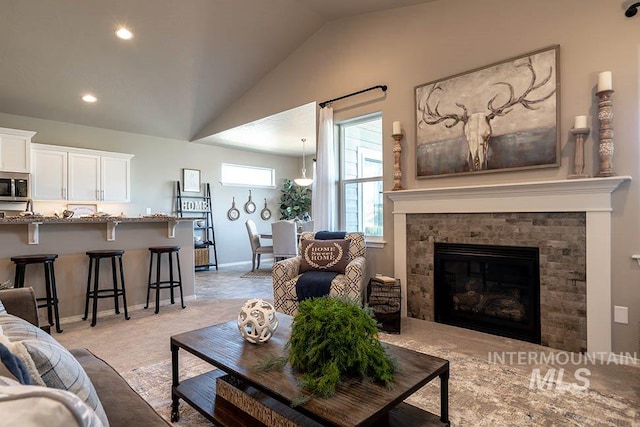 living area with lofted ceiling, a glass covered fireplace, recessed lighting, and light carpet