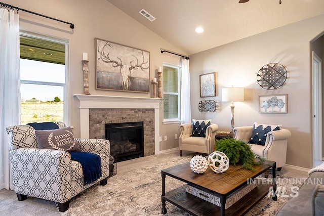 carpeted living area with baseboards, visible vents, a fireplace, and lofted ceiling