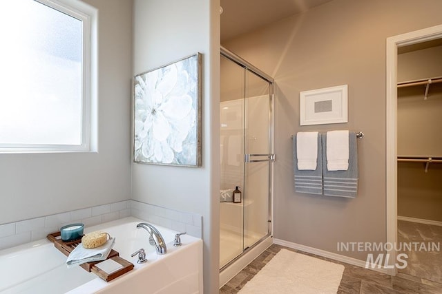 full bath featuring a spacious closet, a shower stall, and a bath