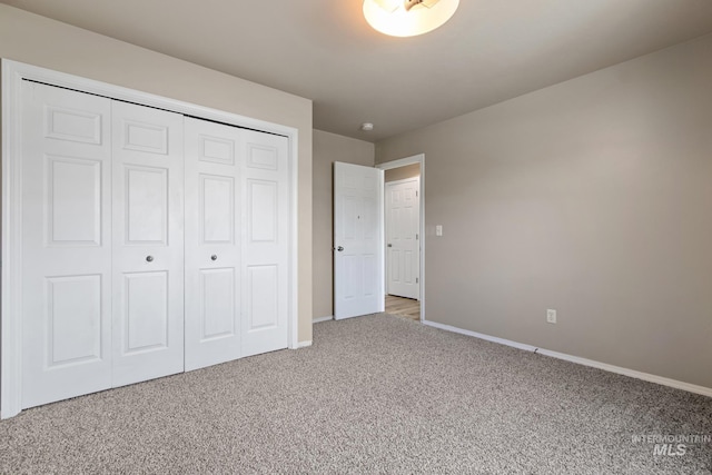 unfurnished bedroom with carpet, a closet, and baseboards