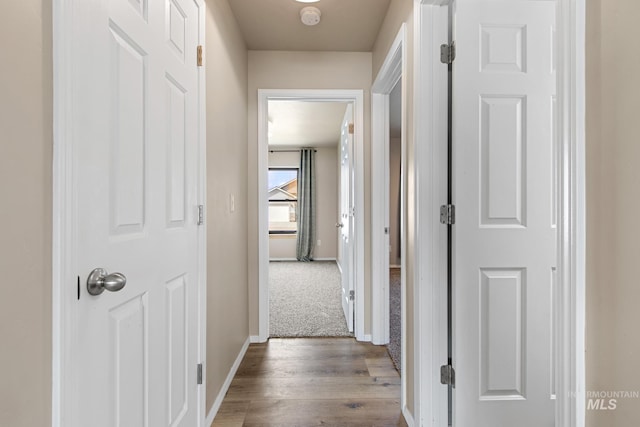 corridor with wood finished floors and baseboards