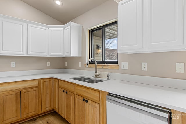 kitchen featuring white cabinets, white dishwasher, a sink, light countertops, and vaulted ceiling