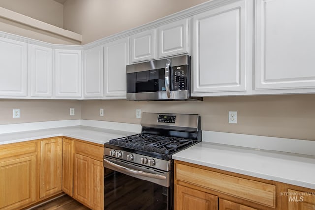 kitchen with appliances with stainless steel finishes, light countertops, and white cabinets
