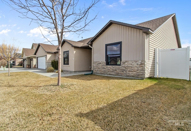 ranch-style home featuring a front lawn, fence, stone siding, and concrete driveway
