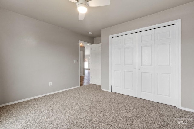unfurnished bedroom featuring a closet, carpet flooring, a ceiling fan, and baseboards