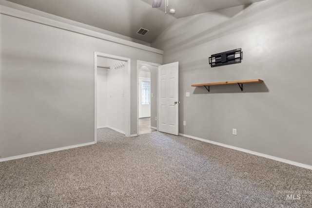 unfurnished bedroom featuring visible vents, baseboards, vaulted ceiling, carpet floors, and arched walkways