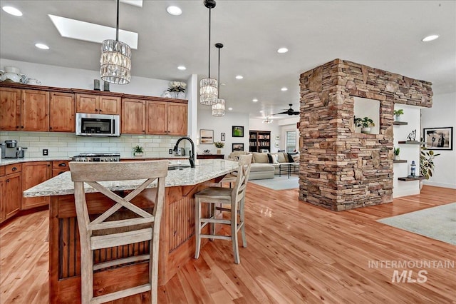 178 Cottonwood Ct, Eagle, ID 83616 - kitchen with a sink, stainless steel microwave, open floor plan, light wood-style floors, and a skylight