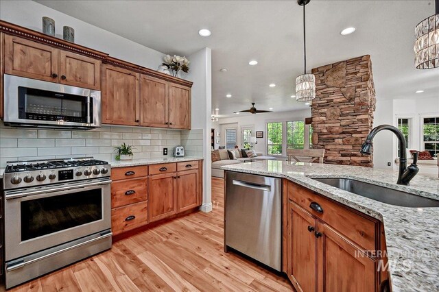 178 Cottonwood Ct, Eagle, ID 83616 - kitchen featuring a sink, stainless steel appliances, open floor plan, backsplash, and light wood-style floors