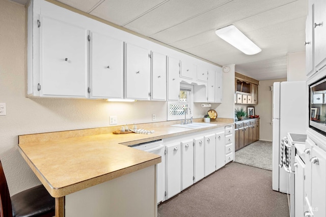 kitchen with sink, white cabinets, white dishwasher, and kitchen peninsula