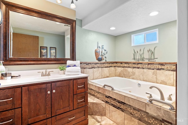 bathroom featuring vanity, tiled bath, and a textured ceiling