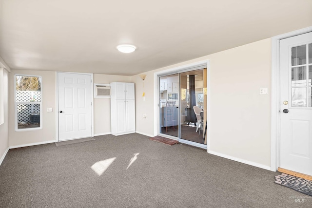 unfurnished bedroom featuring two closets, a wall mounted AC, and dark colored carpet