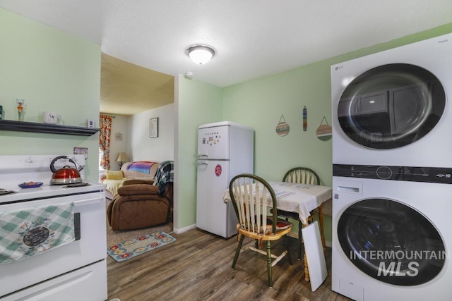 clothes washing area featuring laundry area, wood finished floors, and stacked washer and clothes dryer