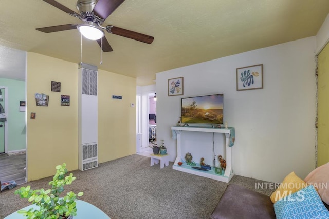 living area featuring a heating unit, carpet, and a ceiling fan