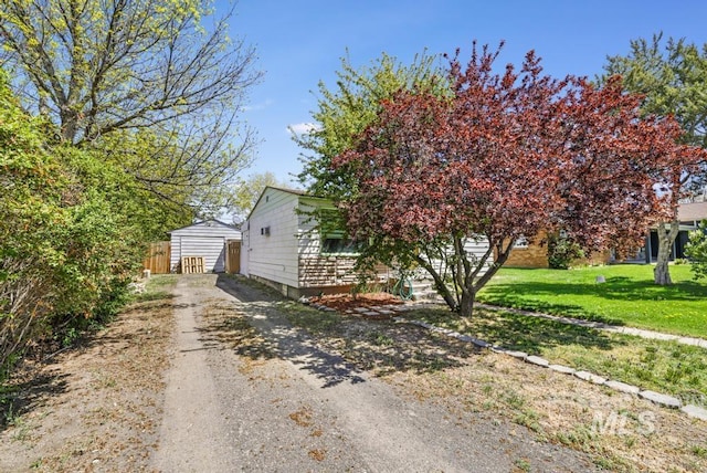view of side of property featuring a yard, driveway, and an outbuilding