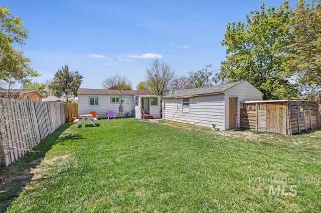 back of house with an outdoor structure, a fenced backyard, a shed, and a yard