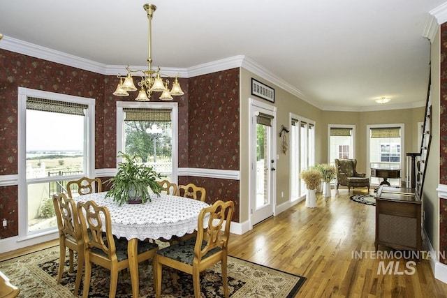 dining room with wallpapered walls, an inviting chandelier, and plenty of natural light