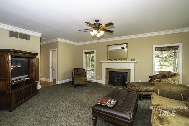 living area featuring visible vents, ornamental molding, ceiling fan, carpet floors, and a fireplace with flush hearth