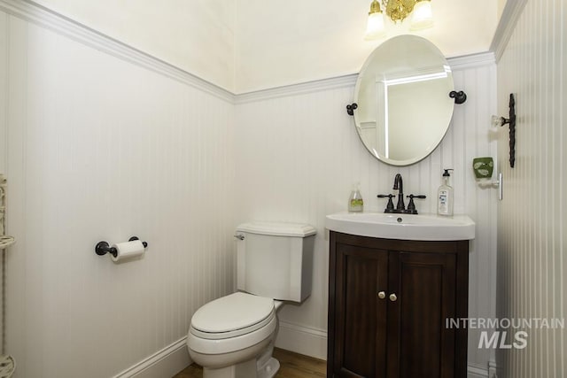 bathroom featuring toilet, wood finished floors, vanity, and baseboards