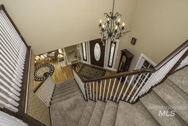 entryway featuring a chandelier, stairs, a towering ceiling, and wood finished floors