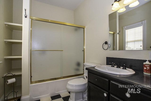 bathroom with toilet, combined bath / shower with glass door, and vanity