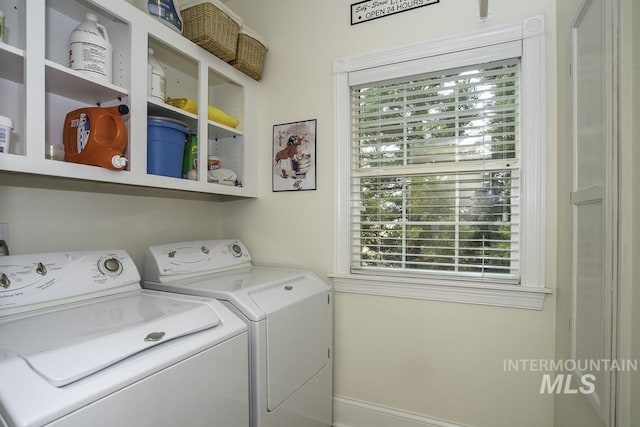 washroom featuring baseboards, separate washer and dryer, and laundry area