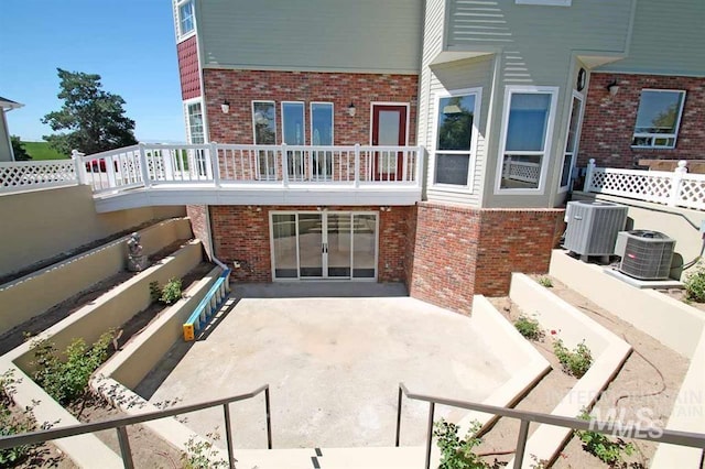 rear view of house with a patio area, brick siding, and central AC unit