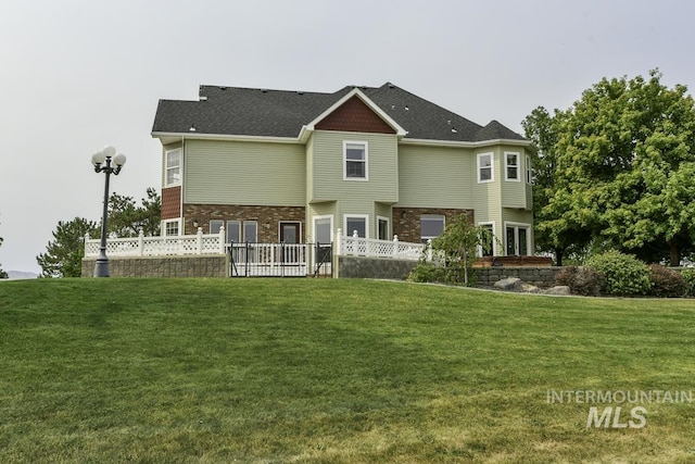 rear view of property with brick siding, fence, and a lawn