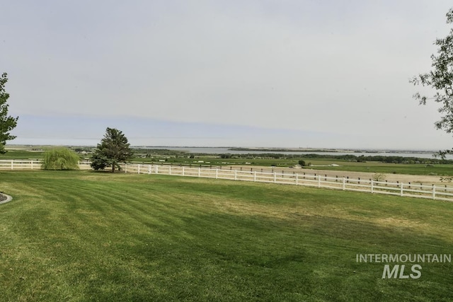 view of yard with fence and a rural view