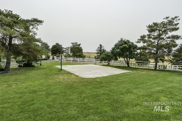 surrounding community with a yard, fence, and basketball hoop