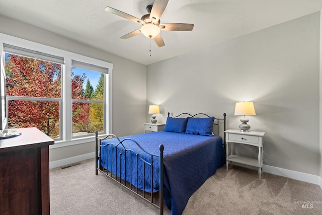 bedroom featuring multiple windows, ceiling fan, and light colored carpet