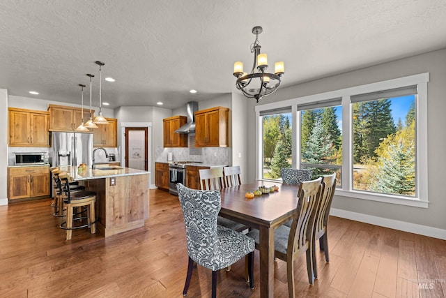 dining room with a textured ceiling, wood-type flooring, sink, and a notable chandelier