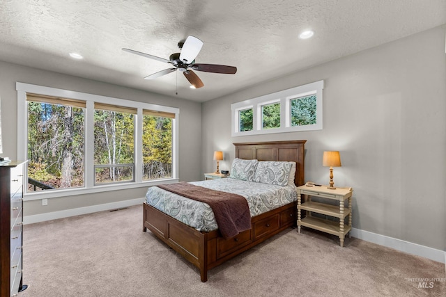 carpeted bedroom with ceiling fan and a textured ceiling