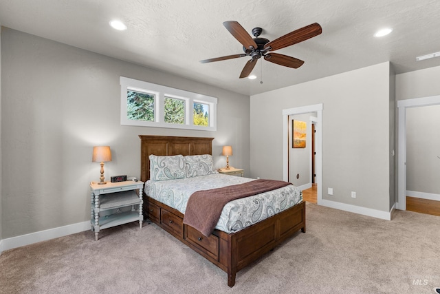 bedroom with ceiling fan, light colored carpet, and a textured ceiling