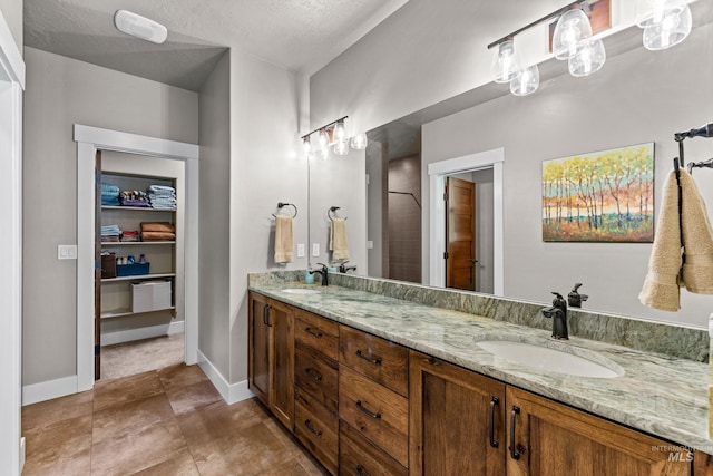 bathroom with a textured ceiling, a shower, and vanity