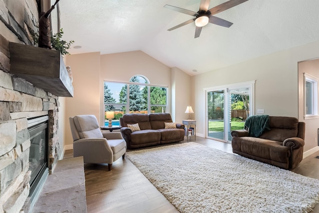 living area featuring lofted ceiling, a fireplace, a wealth of natural light, and light wood-style floors