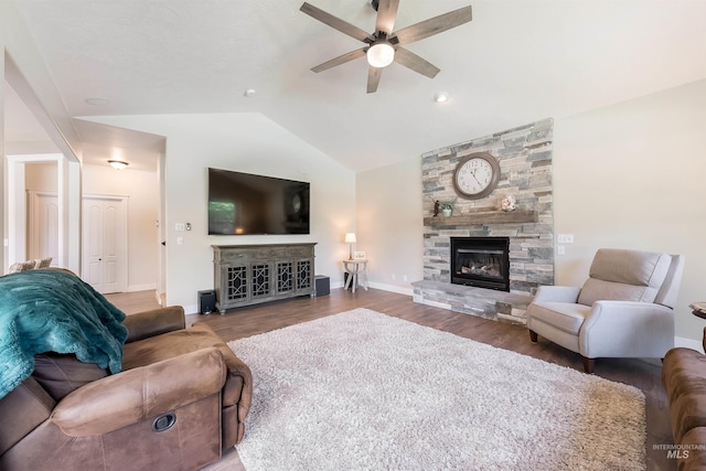 living room with ceiling fan, a fireplace, wood finished floors, baseboards, and vaulted ceiling