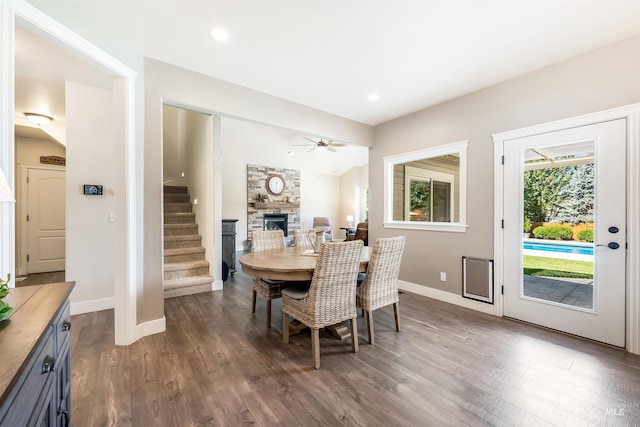 dining room with baseboards, a fireplace, stairway, and dark wood finished floors